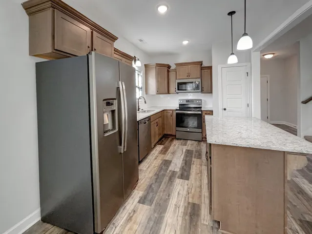 a kitchen with stainless steel appliances granite countertop a refrigerator a stove and a sink with wooden floor