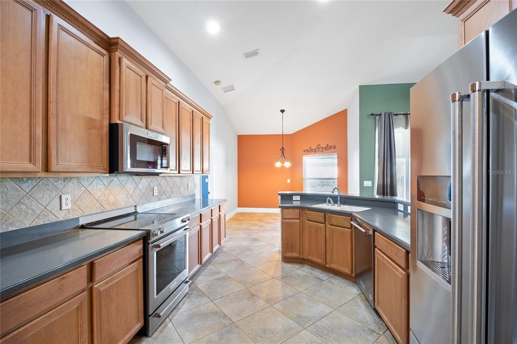 13413 Mandalay Place Spring Hill, FL 34609 - Photo 17 of 46 a large kitchen with stainless steel appliances granite countertop a stove and a sink