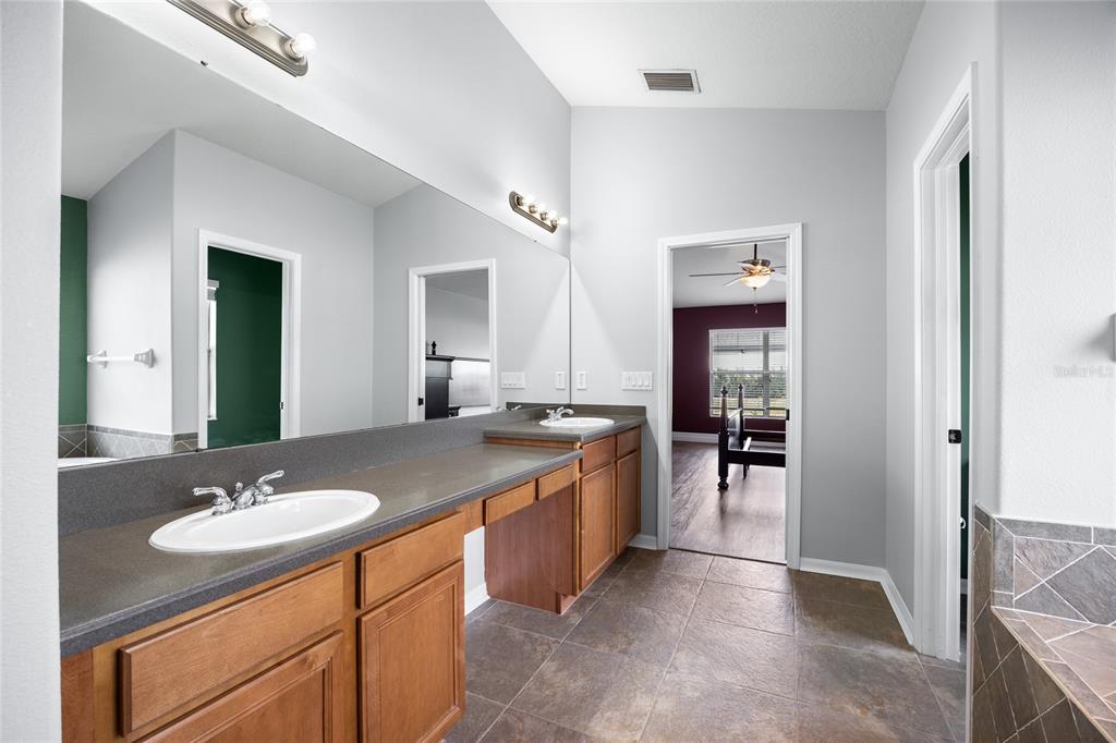 13413 Mandalay Place Spring Hill, FL 34609 - Photo 24 of 46 a bathroom with a sink double vanity granite tub shower and a mirror