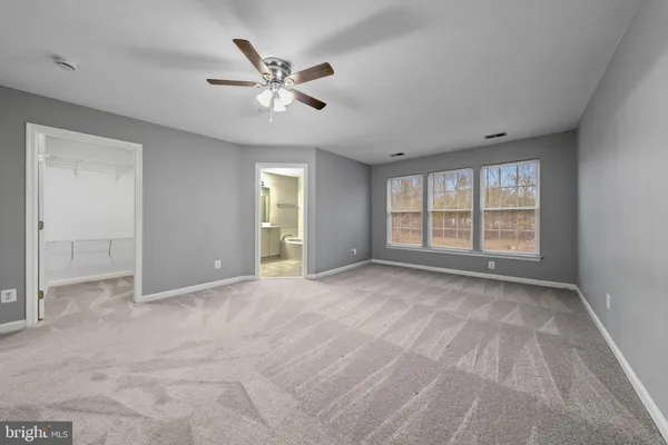 a view of an empty room with chandelier fan and fire place