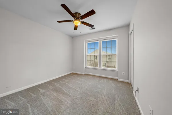 an empty room with ceiling fan and window