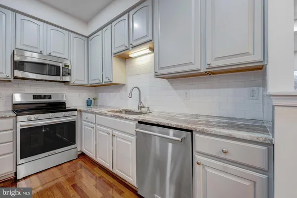 a kitchen with granite countertop white cabinets stainless steel appliances and sink