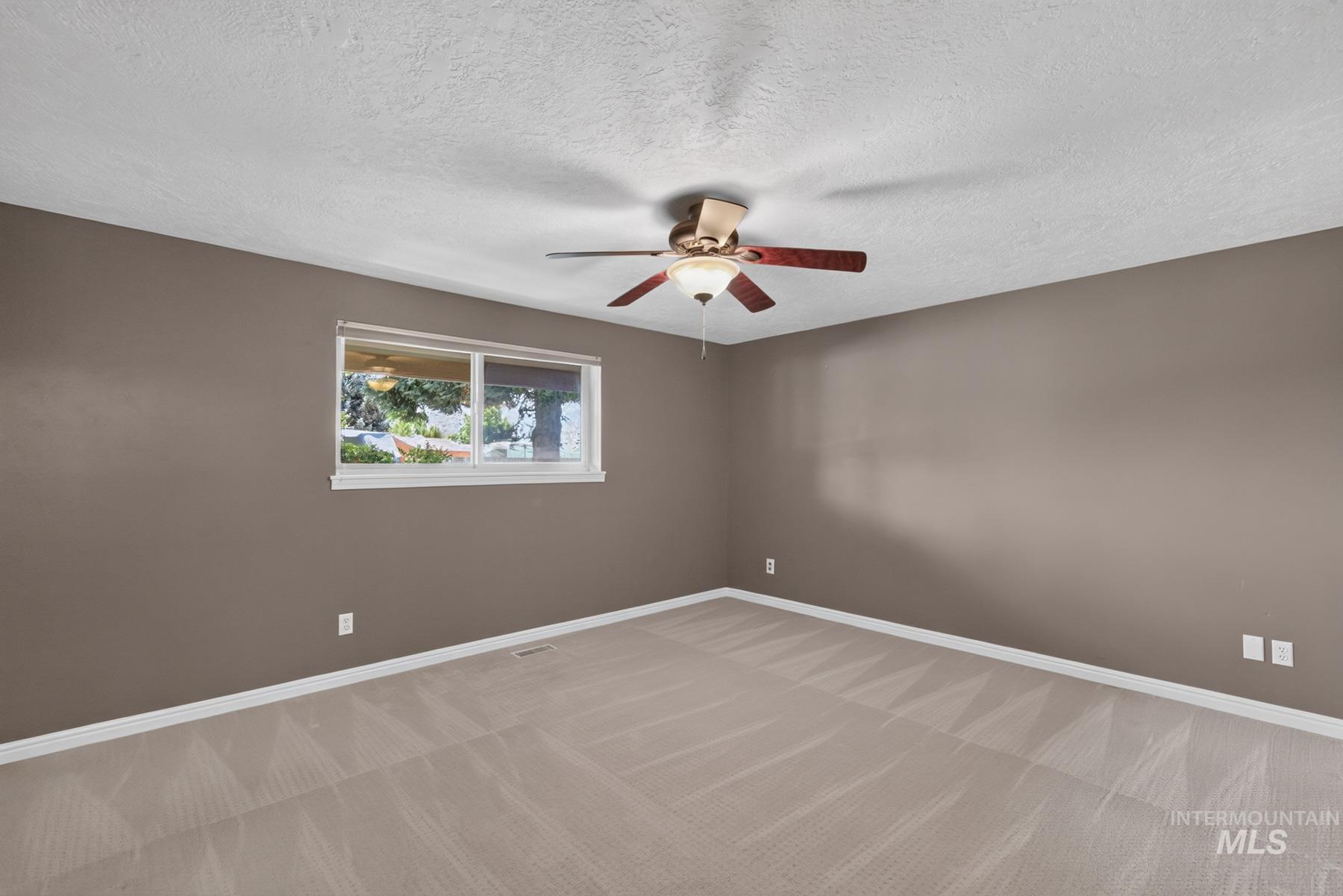 9622 Delaware Street Boise, ID 83709 - Photo 27 of 48 Neutral-toned room featuring a window with white trim, a wood-finish ceiling fan with integrated lighting, and light-colored carpet flooring