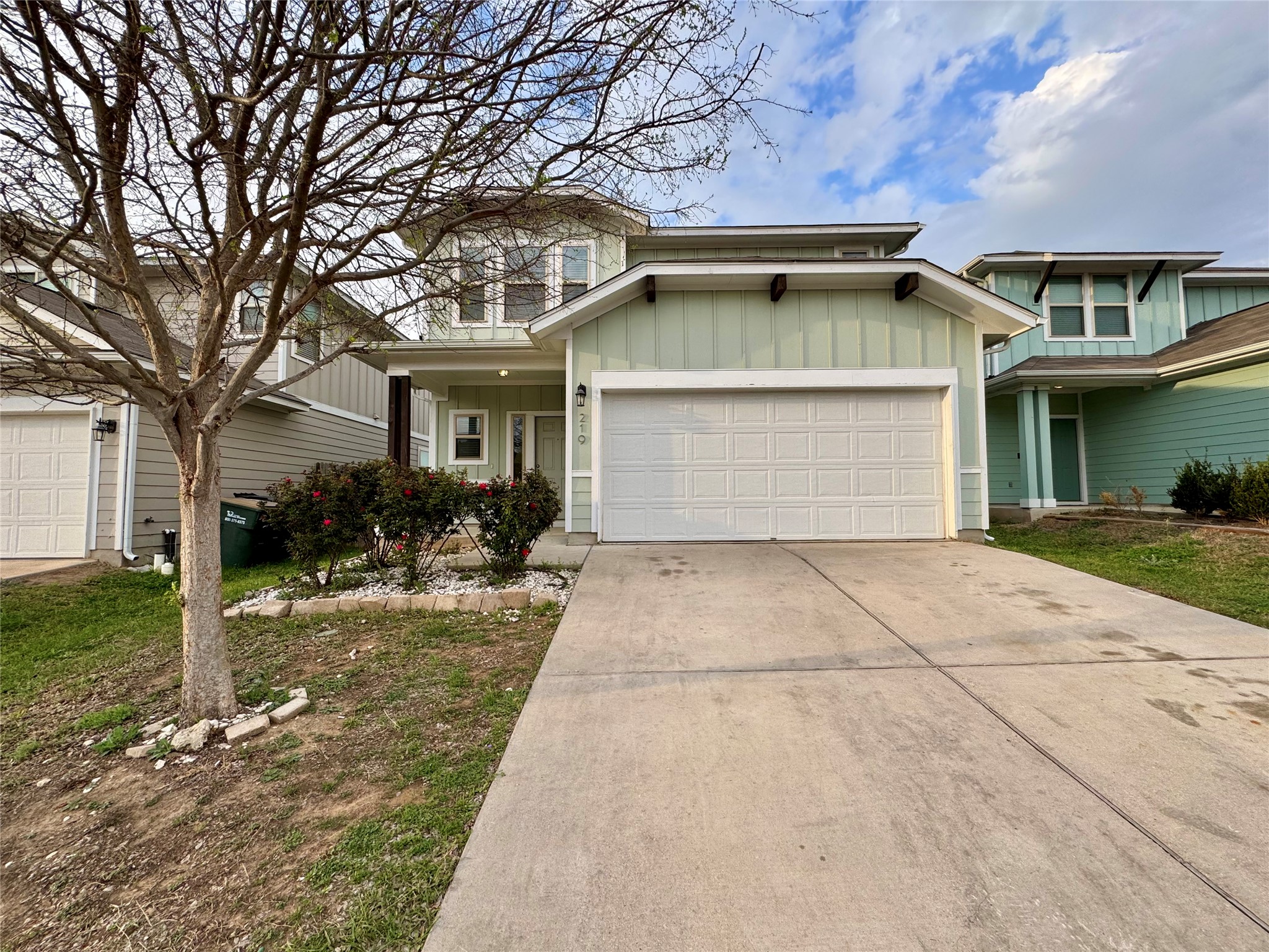 Traditional home with board and batten siding, driveway, an attached garage, and a porch