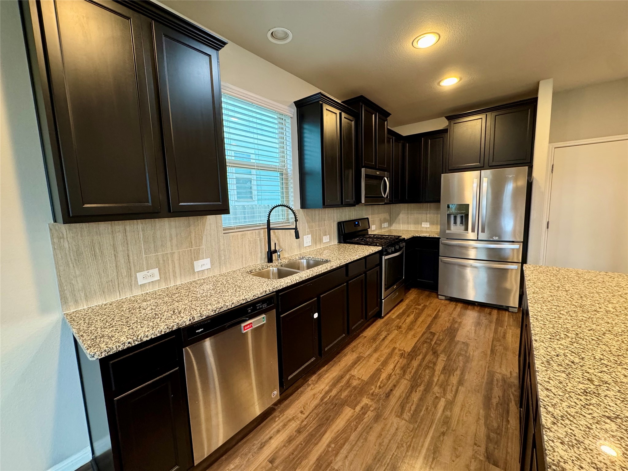 219 Wapiti Road Buda, TX 78610 - Photo 11 of 24 a kitchen with stainless steel appliances granite countertop a sink stove and refrigerator