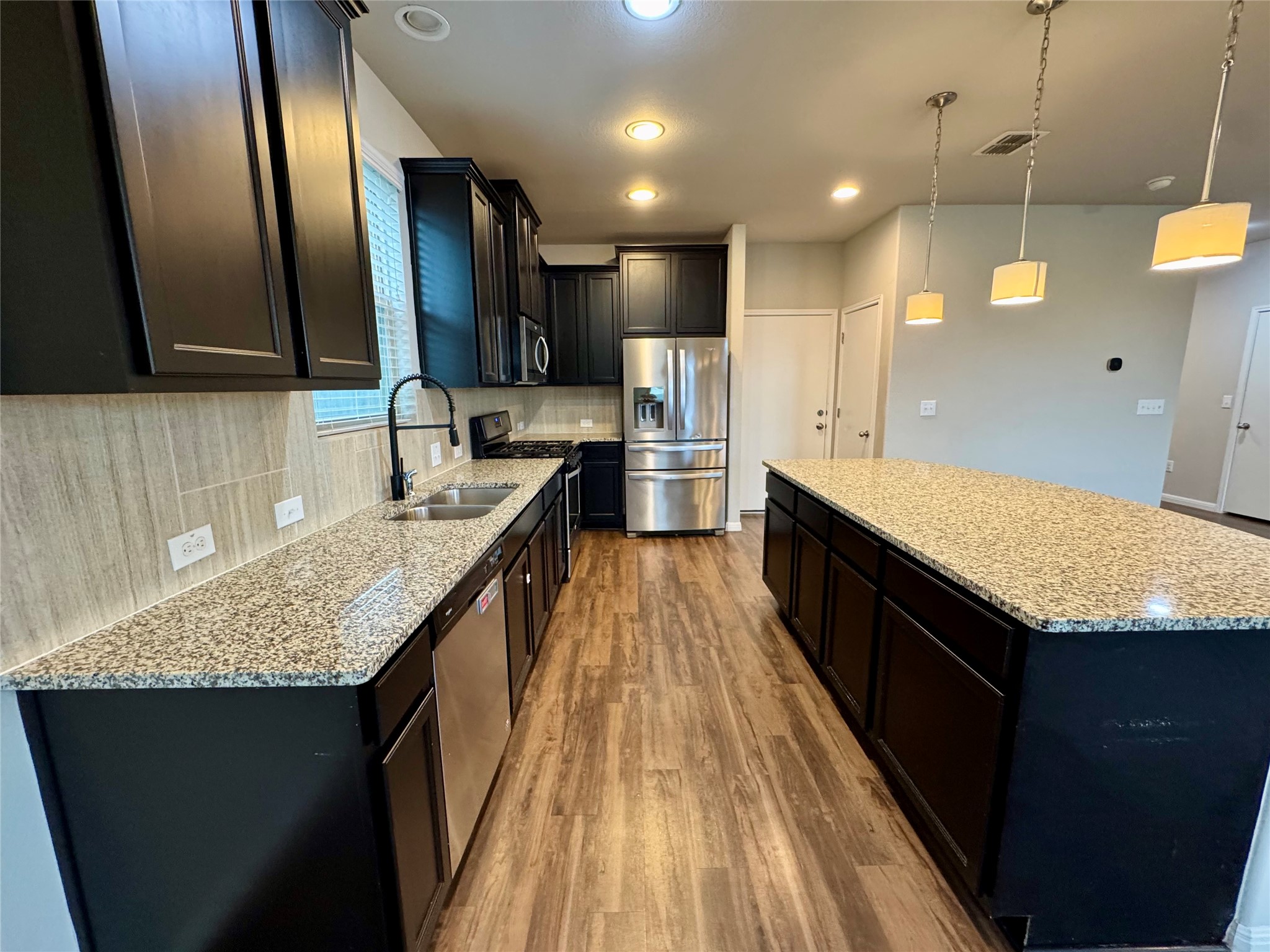 219 Wapiti Road Buda, TX 78610 - Photo 12 of 24 a kitchen with kitchen island granite countertop a sink stove and refrigerator