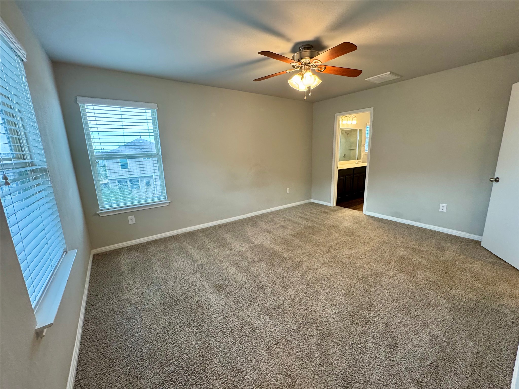 219 Wapiti Road Buda, TX 78610 - Photo 14 of 24 Unfurnished bedroom with dark carpet, a ceiling fan, and ensuite bath