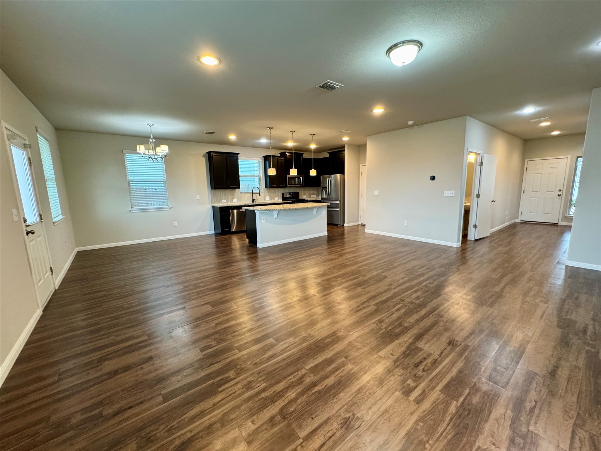 219 Wapiti Road Buda, TX 78610 - Photo 5 of 24 Unfurnished living room featuring hanging lights and dark wood finished floors