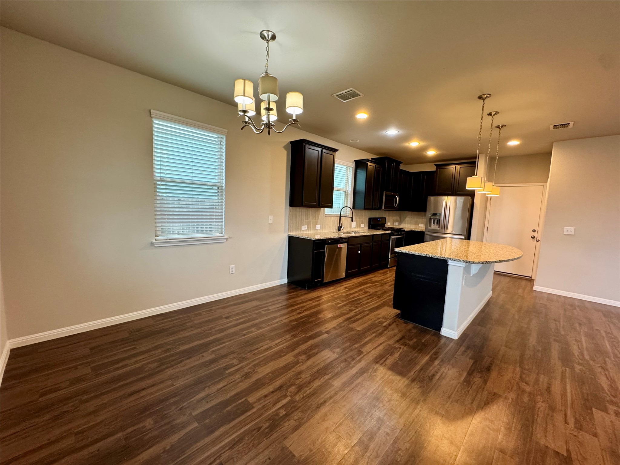 219 Wapiti Road Buda, TX 78610 - Photo 6 of 24 Kitchen featuring stainless steel appliances, a chandelier, healthy amount of natural light, and a center island