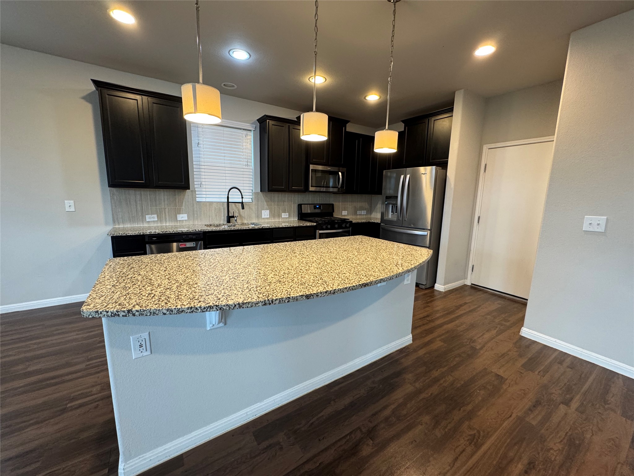 219 Wapiti Road Buda, TX 78610 - Photo 8 of 24 a large kitchen with a large counter top space a sink stainless steel appliances and cabinets