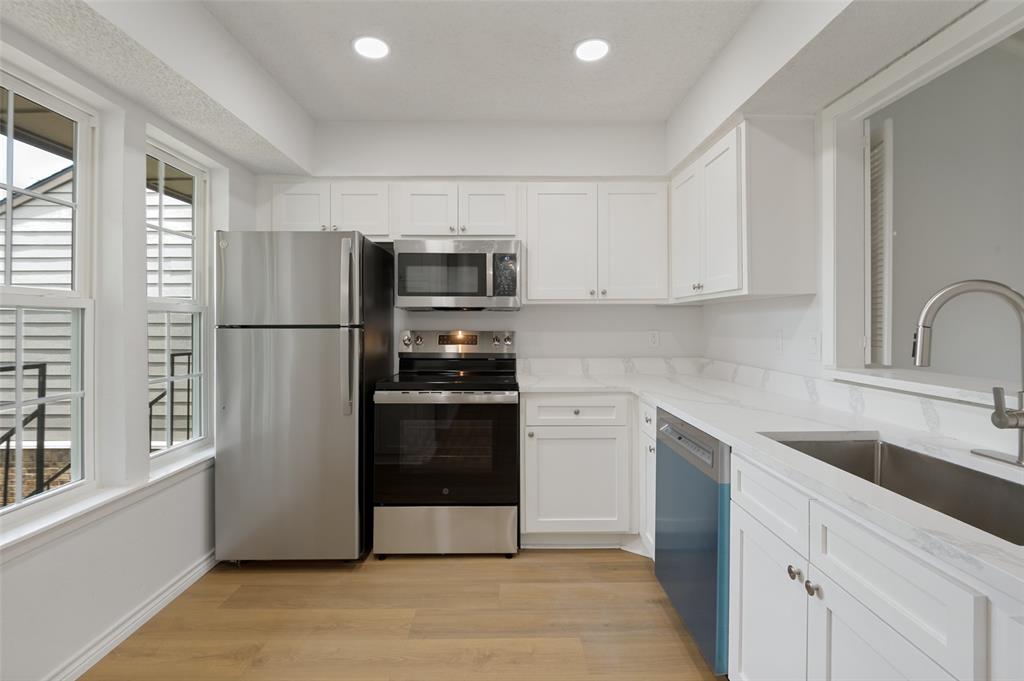 5300 Keller Springs Road, Unit 2042 Dallas, TX 75248 - Photo 5 of 28 Kitchen featuring wood-finish flooring, white cabinetry with silver hardware, stainless steel appliances, and white countertops
