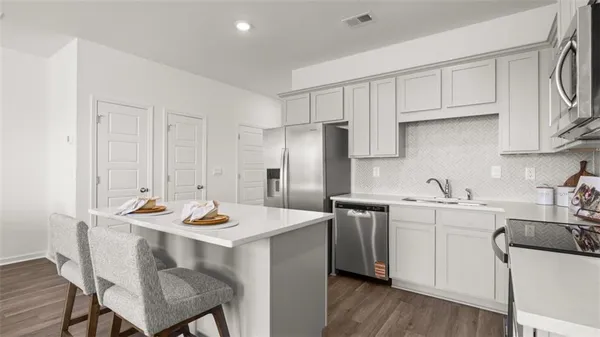 a kitchen with stainless steel appliances kitchen island a table chairs sink and cabinets