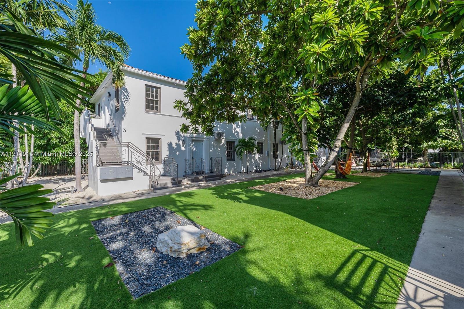 415 75th Street, Unit 1A Miami Beach, FL 33141 - Photo 1 of 19 a view of a yard with plants and a large tree