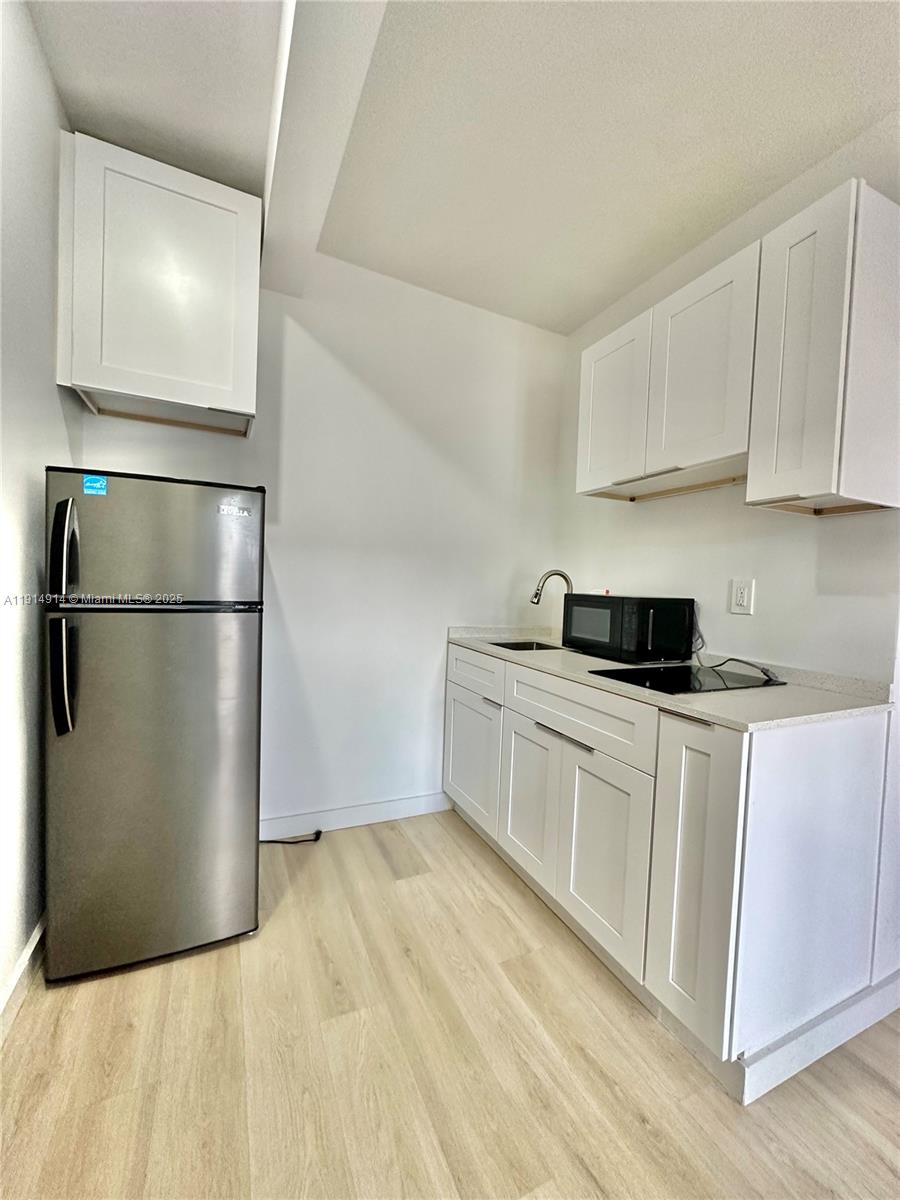 415 75th Street, Unit 1A Miami Beach, FL 33141 - Photo 9 of 19 a kitchen with a refrigerator and white cabinets