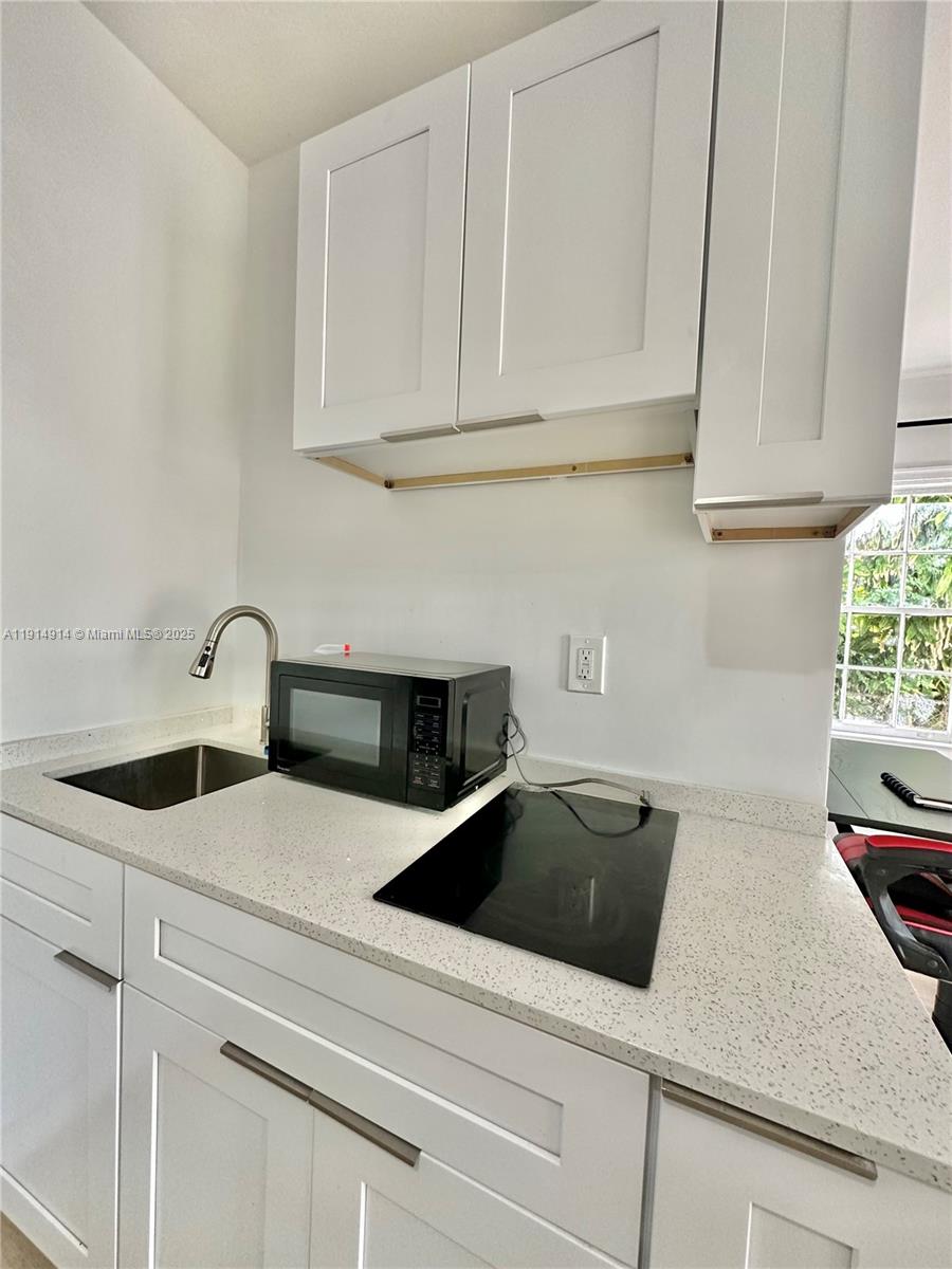 415 75th Street, Unit 1A Miami Beach, FL 33141 - Photo 10 of 19 a kitchen with granite countertop white cabinets and white appliances