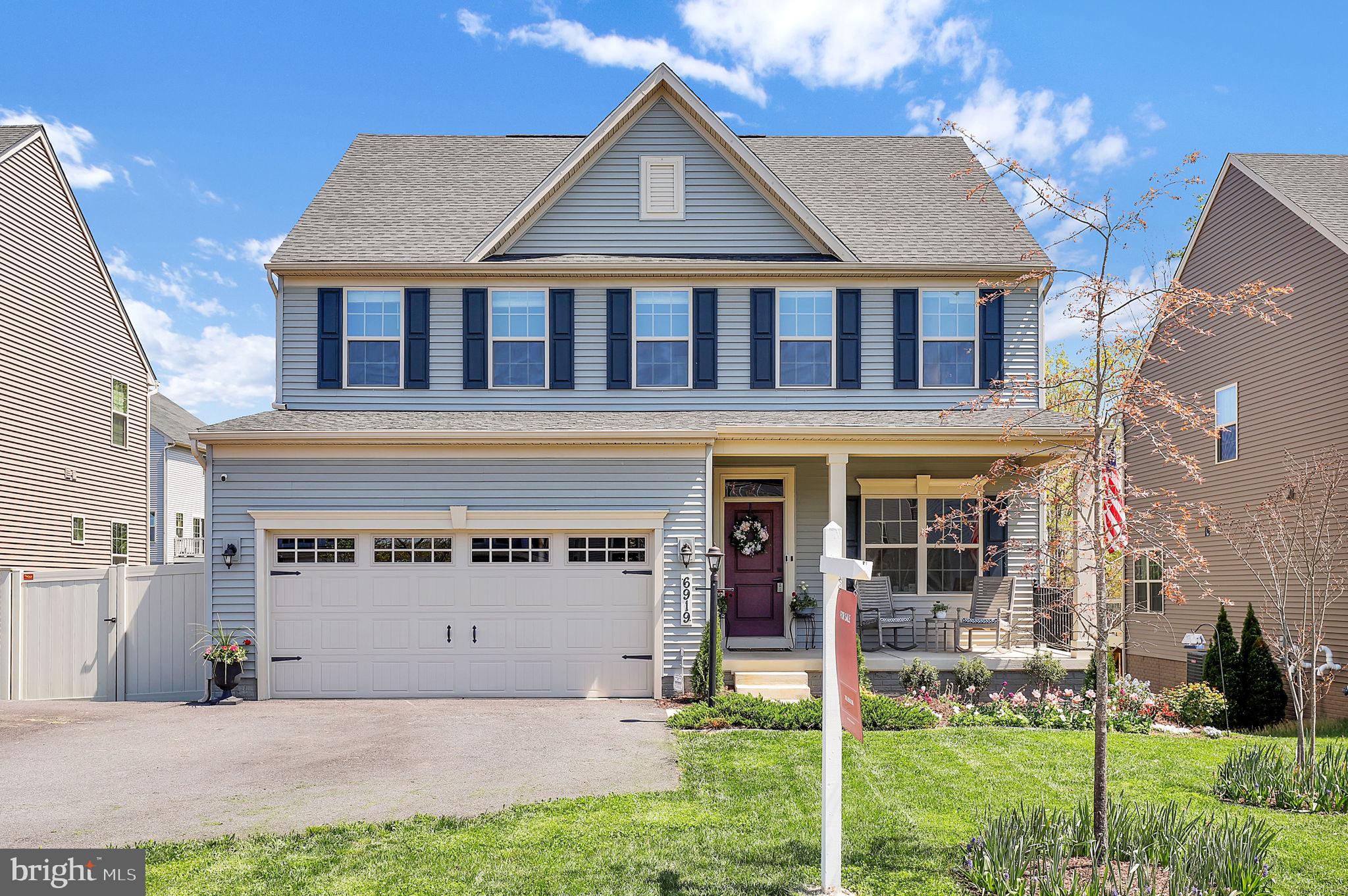 a view of a white house with large windows and a yard with plants and large trees