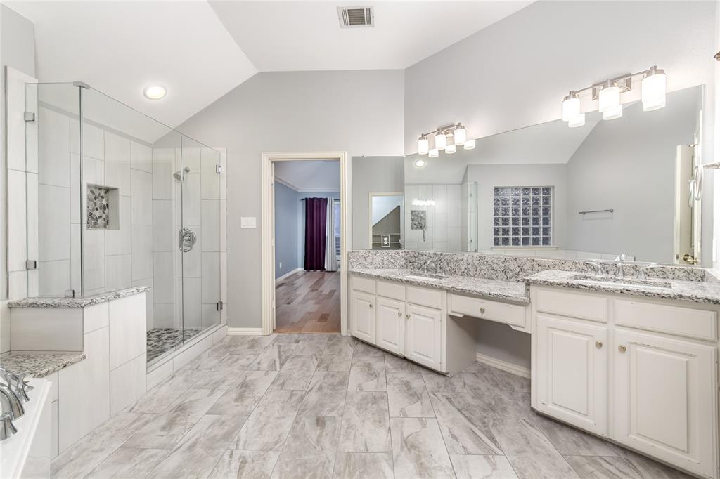 5801 Yeary Road Plano, TX 75093 - Photo 27 of 33 Spacious bathroom featuring dual vanities with light-colored countertops, a large frameless glass shower enclosure, and grey-toned tile flooring