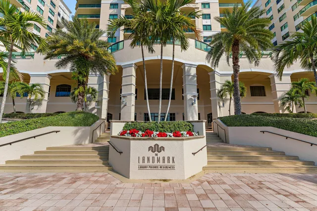 a front view of multi story residential apartment building with yard and sign board