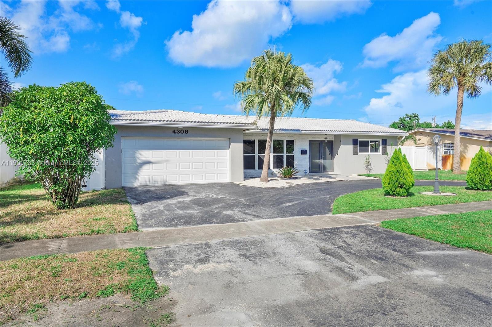 4309 Jackson Street Hollywood, FL 33021 - Photo 2 of 39 a front view of a house with a yard and a garage