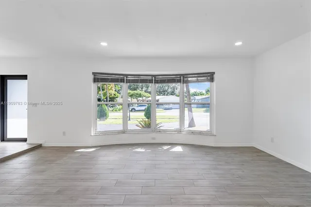 an empty room with wooden floor and outdoor view