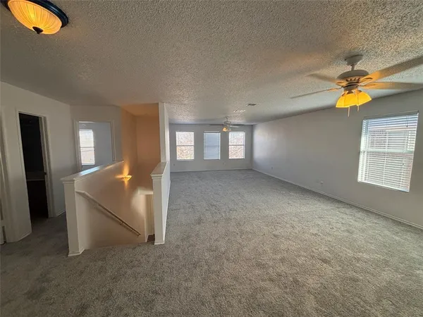 an empty room with windows and ceiling fan