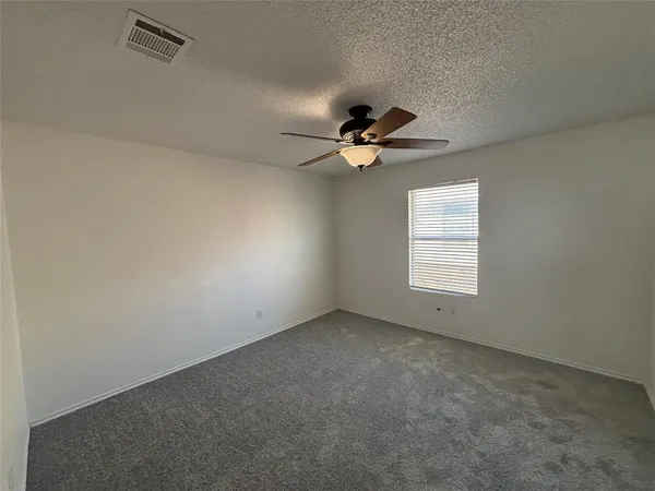 an empty room with a ceiling fan and window