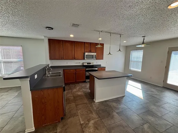 a kitchen with stainless steel appliances granite countertop a sink a stove and a refrigerator