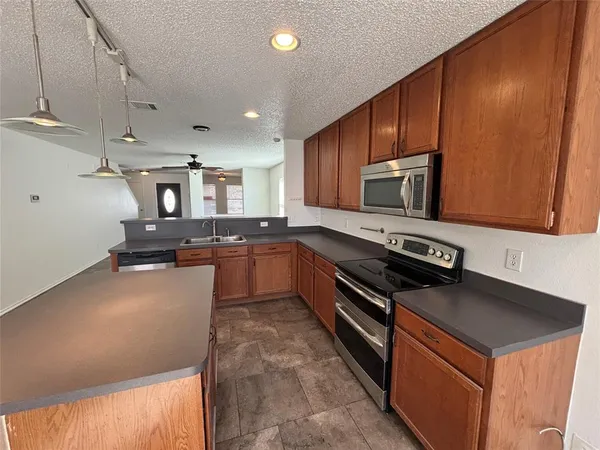 a large kitchen with stainless steel appliances wooden cabinets a stove and a refrigerator