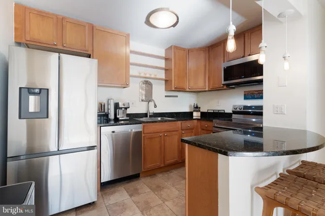 a kitchen with stainless steel appliances granite countertop a refrigerator a stove a sink and a microwave