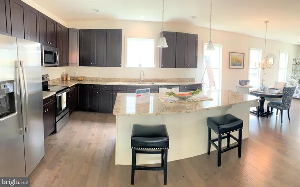 a kitchen with stainless steel appliances granite countertop a stove refrigerator and a chair