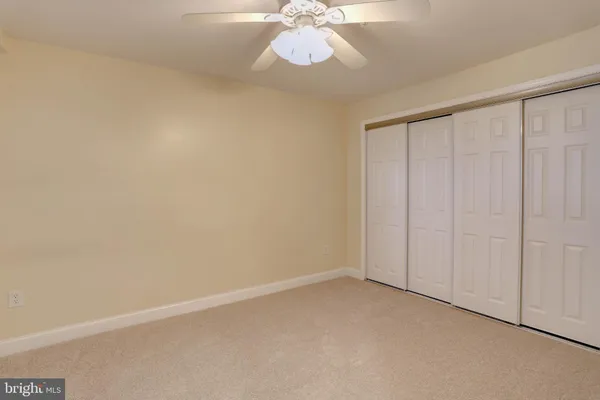 an empty room with chandelier fan and windows