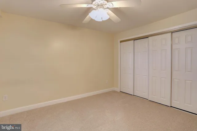 an empty room with chandelier fan and windows