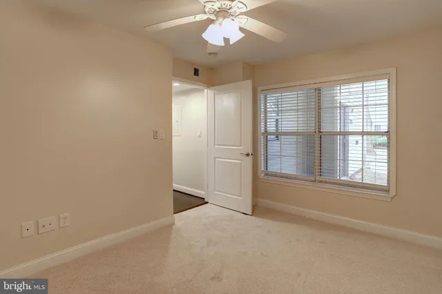 an empty room with chandelier fan and windows
