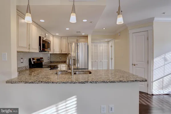 a kitchen with kitchen island granite countertop stainless steel appliances sink stove microwave and cabinets