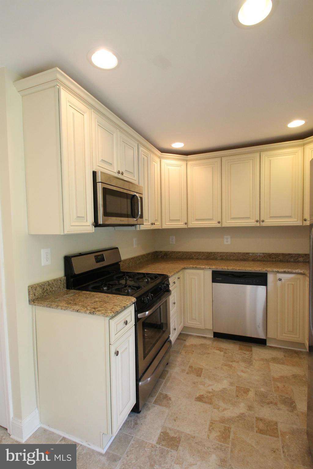 1520 Daytona Road Baltimore, MD 21234 - Photo 9 of 24 a kitchen with granite countertop a stove top oven microwave and cabinets