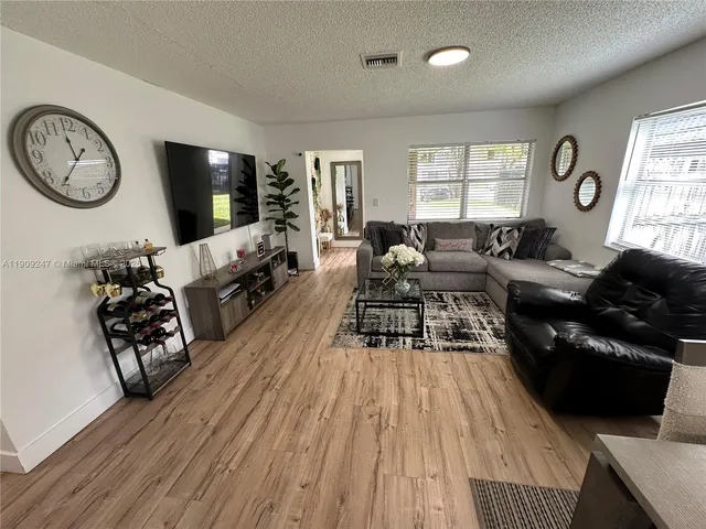 a living room with furniture a large window and wooden floor