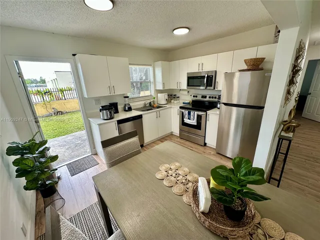 a white kitchen with stainless steel appliances granite countertop a refrigerator a stove a microwave a sink and cabinets