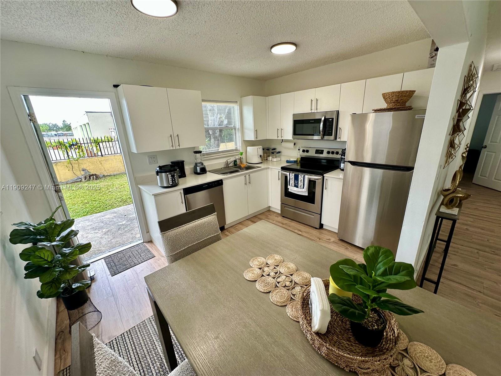 6040 Southwest 35th Street, Unit 2 Miramar, FL 33023 - Photo 6 of 14 a white kitchen with stainless steel appliances granite countertop a refrigerator a stove a microwave a sink and cabinets
