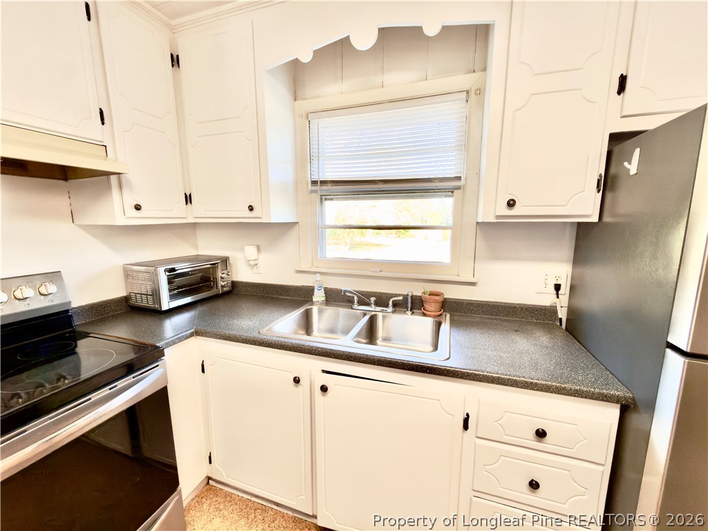 5271 Tobacco Road Orrum, NC 28369 - Photo 11 of 49 a kitchen with granite countertop a sink a stove and cabinets