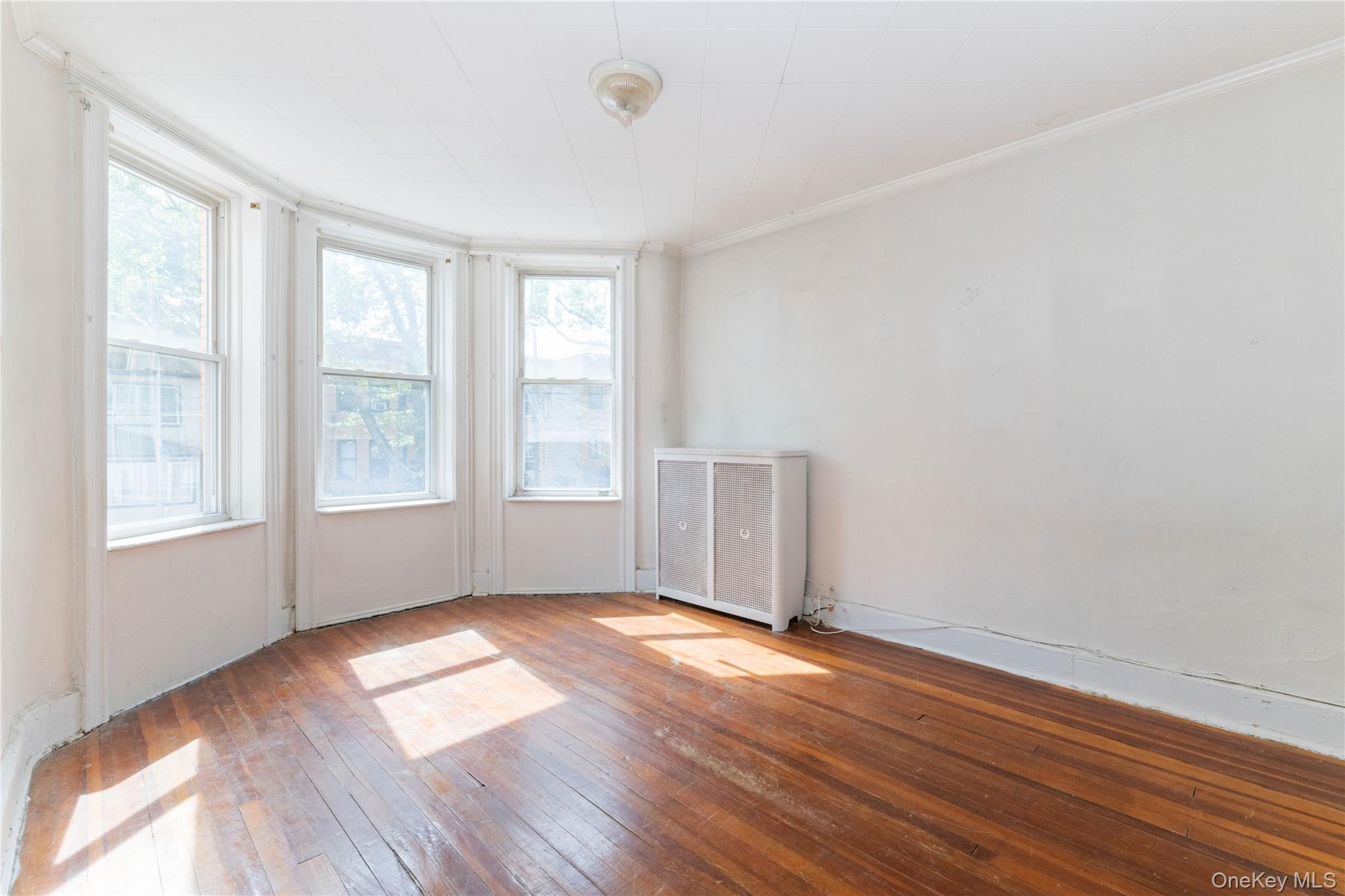82-72 88th Place Queens, NY 11421 - Photo 6 of 26 a view of empty room with wooden floor and fan