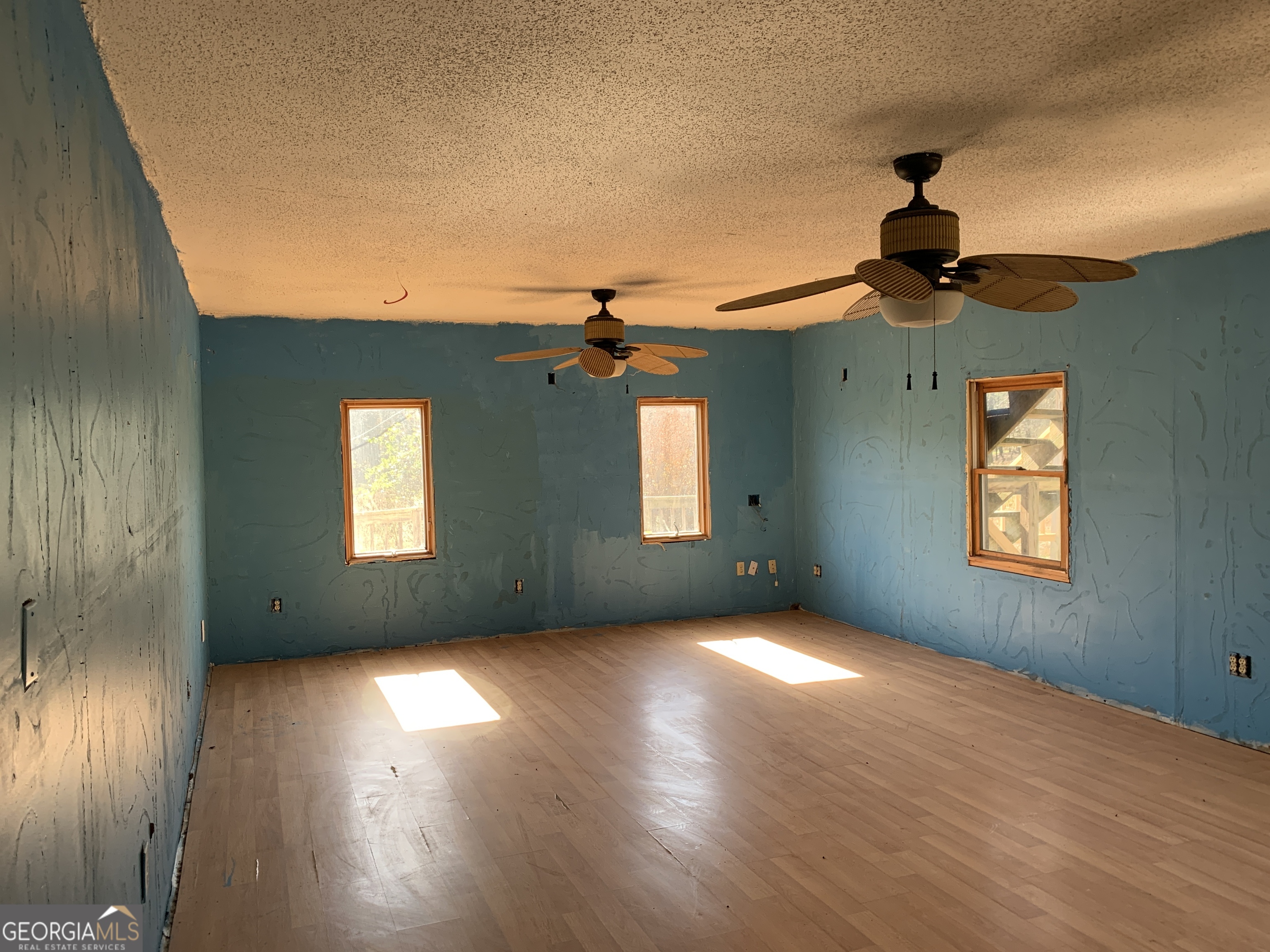 222 Reno Road Royston, GA 30662 - Photo 7 of 15 an empty room with wooden floor chandelier fan and windows