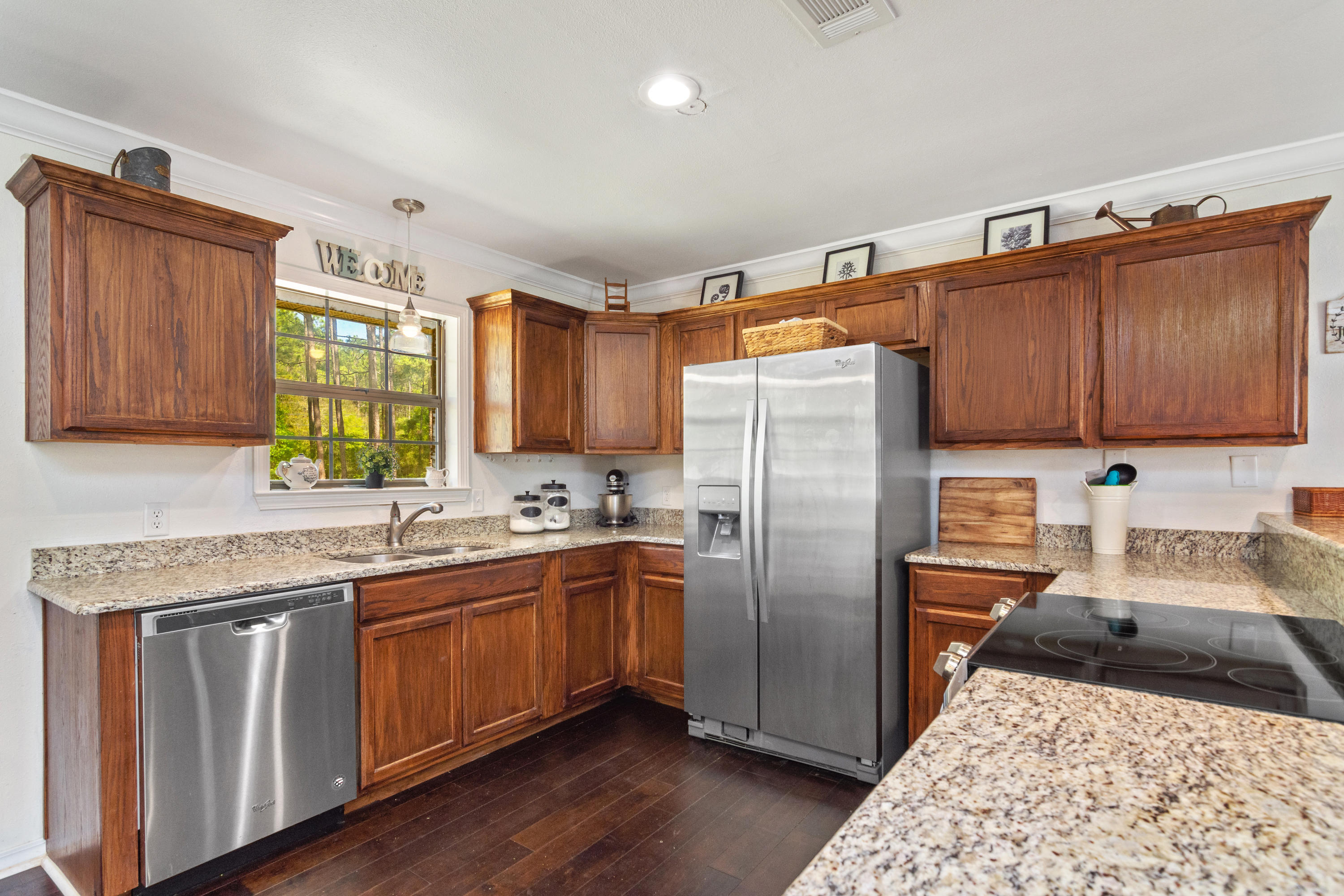 658 Ridge Lake Road Crestview, FL 32536 - Photo 9 of 47 a kitchen with stainless steel appliances granite countertop a refrigerator a sink dishwasher a stove with wooden cabinets and floor