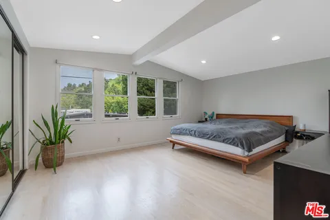 a spacious bedroom with a bed and a flat screen tv