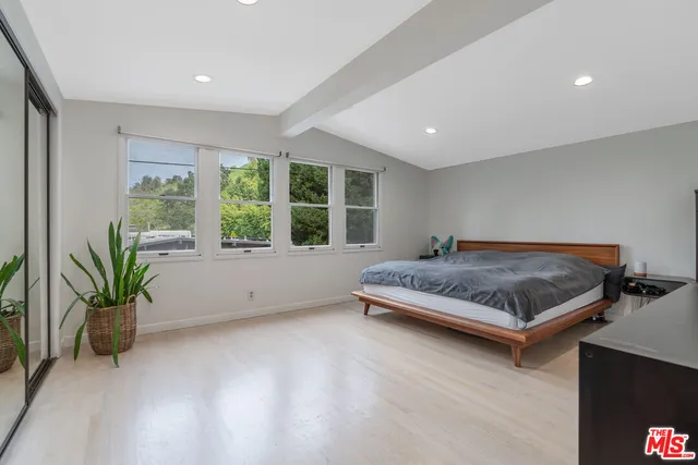 a spacious bedroom with a bed and a flat screen tv