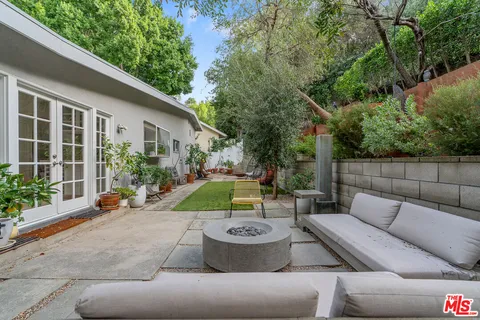 a backyard of a house with table and chairs plants
