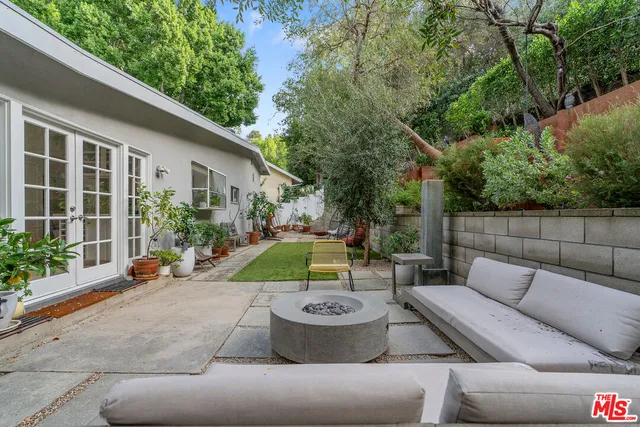 a backyard of a house with table and chairs plants