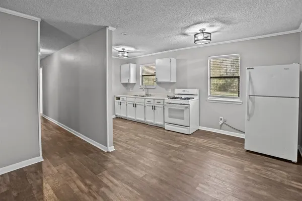 a view of a kitchen with wooden floor electronic appliances and cabinets