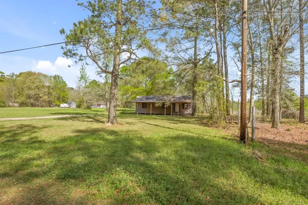 a view of a house with a big yard and large trees