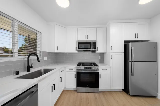 a kitchen with a sink a refrigerator a stove and cabinets