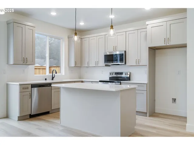 a kitchen with kitchen island white cabinets a sink a window and appliances
